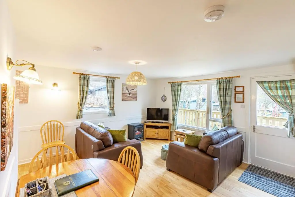 a living room with two couches and a table at Bracken Lodge 6 with Hot Tub in Belladrum