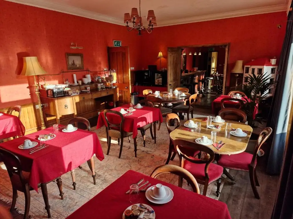 a restaurant with tables and chairs and red walls at Cambus O' May Traditional Highland Hotel in Ballater