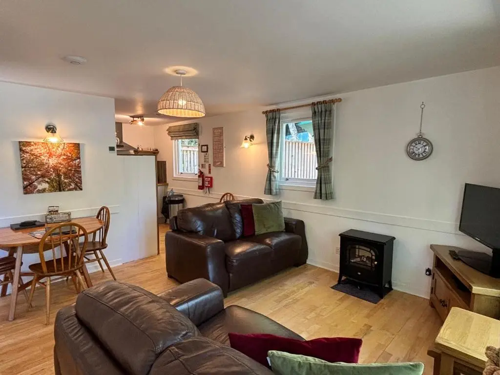 a living room with a leather couch and a table at Bracken Lodge 7 with Hot Tub in Belladrum