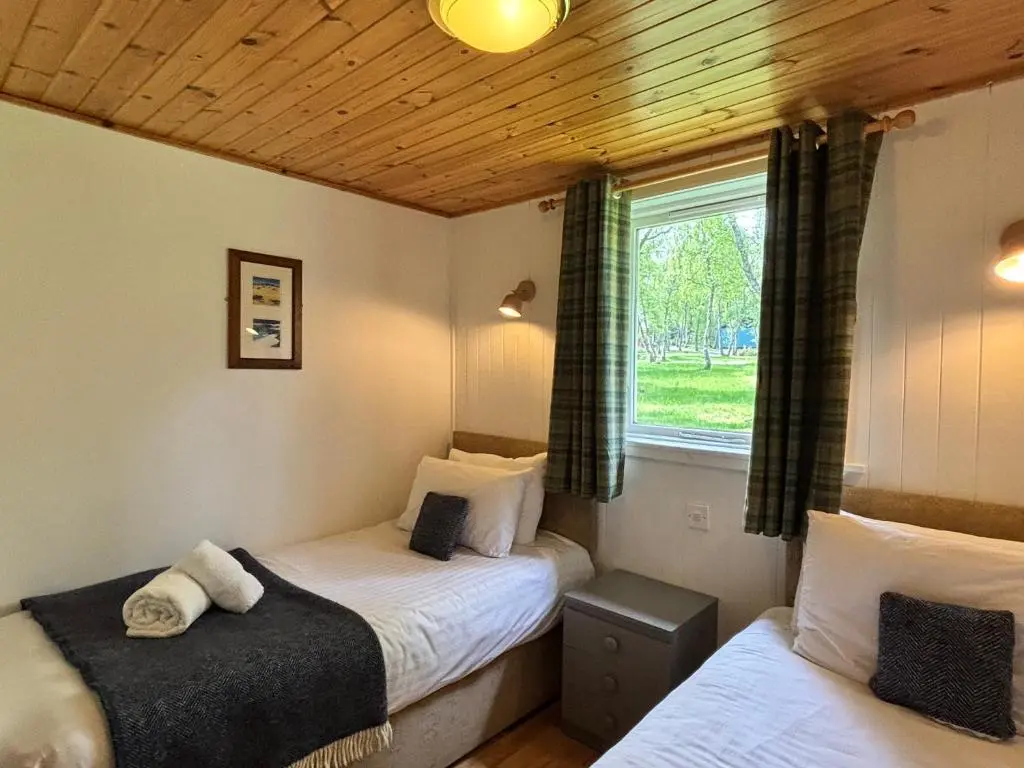 two twin beds in a room with a window at Heather Lodge 17 with Hot Tub in Belladrum