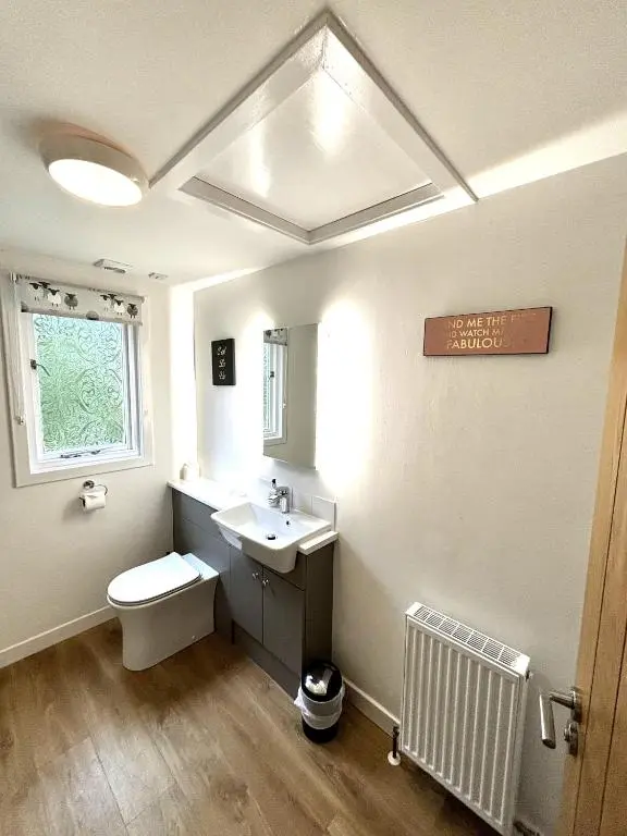 a bathroom with a sink and a toilet and a window at Heather Lodge 17 with Hot Tub in Belladrum