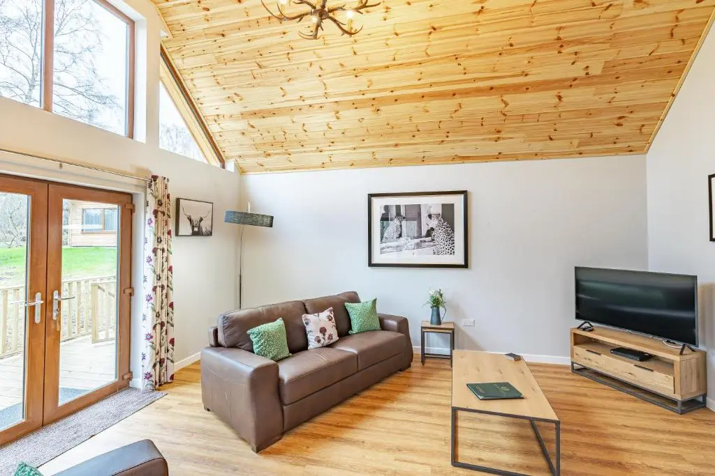 a living room with a couch and a tv at Thistle Lodge 19 with Hot Tub in Belladrum