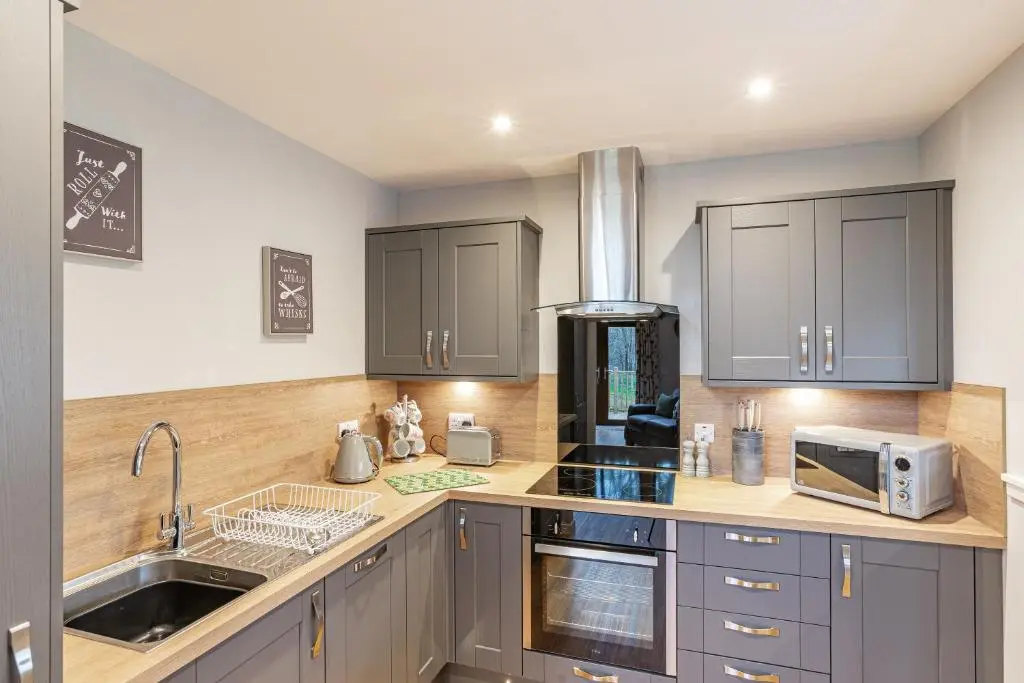 a kitchen with gray cabinets and a sink at Thistle Lodge 19 with Hot Tub in Belladrum