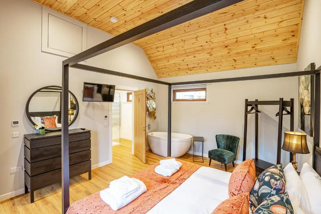 a bedroom with a bed and a bathroom with a tub at Thistle Lodge 19 with Hot Tub in Belladrum