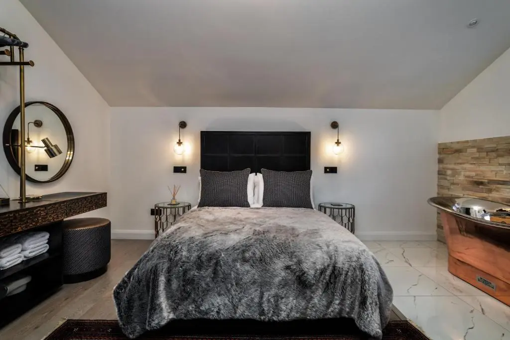a bedroom with a large bed and a sink at Pamper yourself in our DOUBLE SIZED copper tub -2 bedroom villa in Inverness