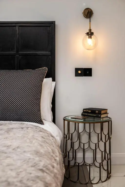 a bed with a black headboard and a side table at Pamper yourself in our DOUBLE SIZED copper tub -2 bedroom villa in Inverness