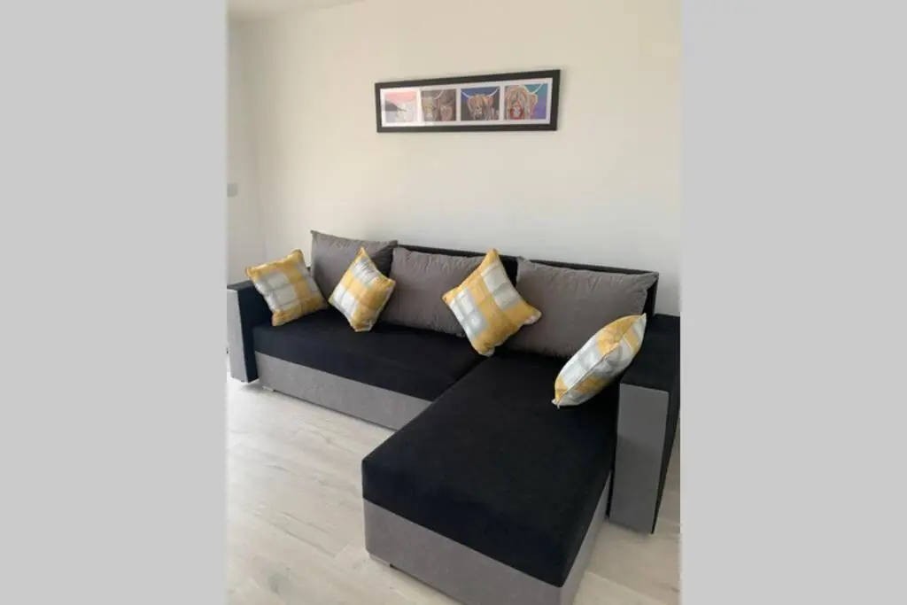 a black couch with pillows in a living room at TomaX Garden Cabin Free Parking in Inverness