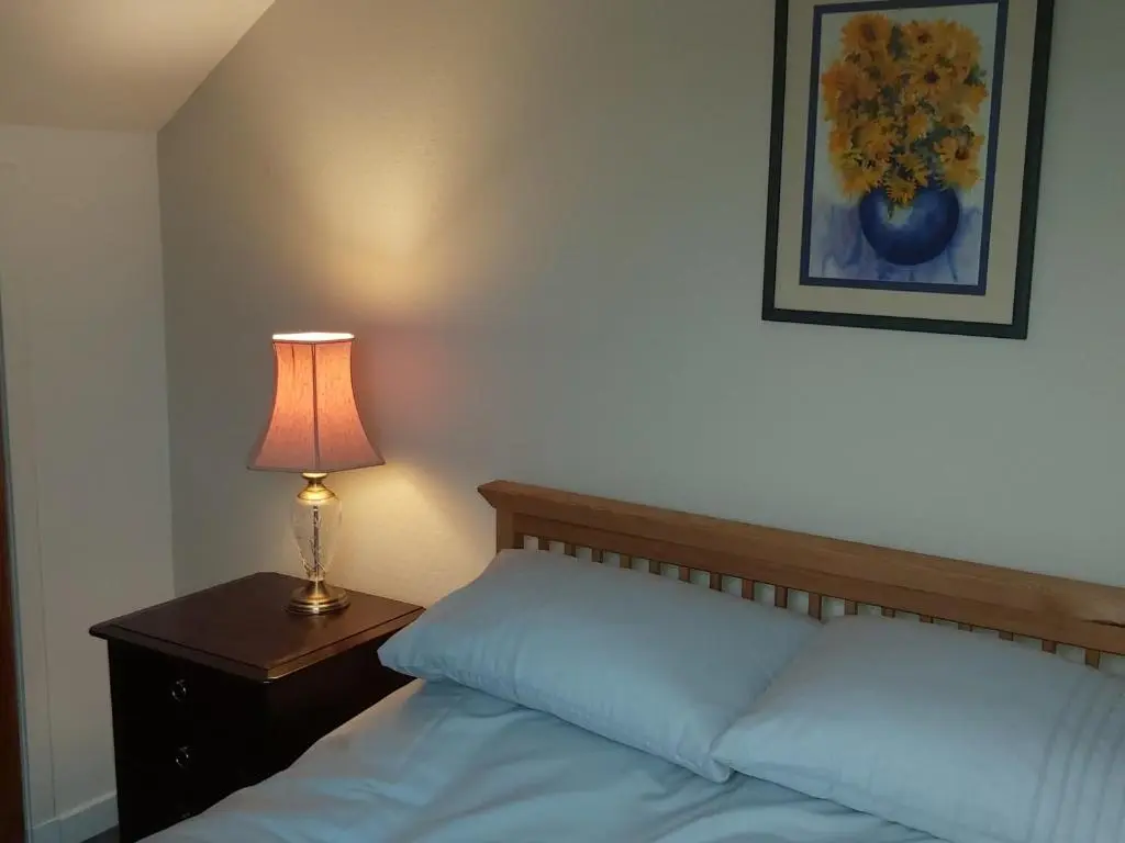 a bedroom with a bed with a lamp on a night stand at Kirkhouse in Wick