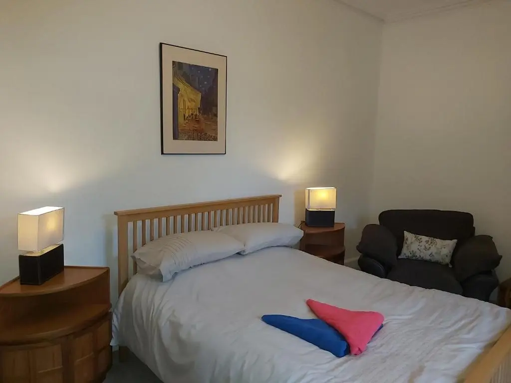 a bedroom with a bed and a chair and two lamps at Kirkhouse in Wick