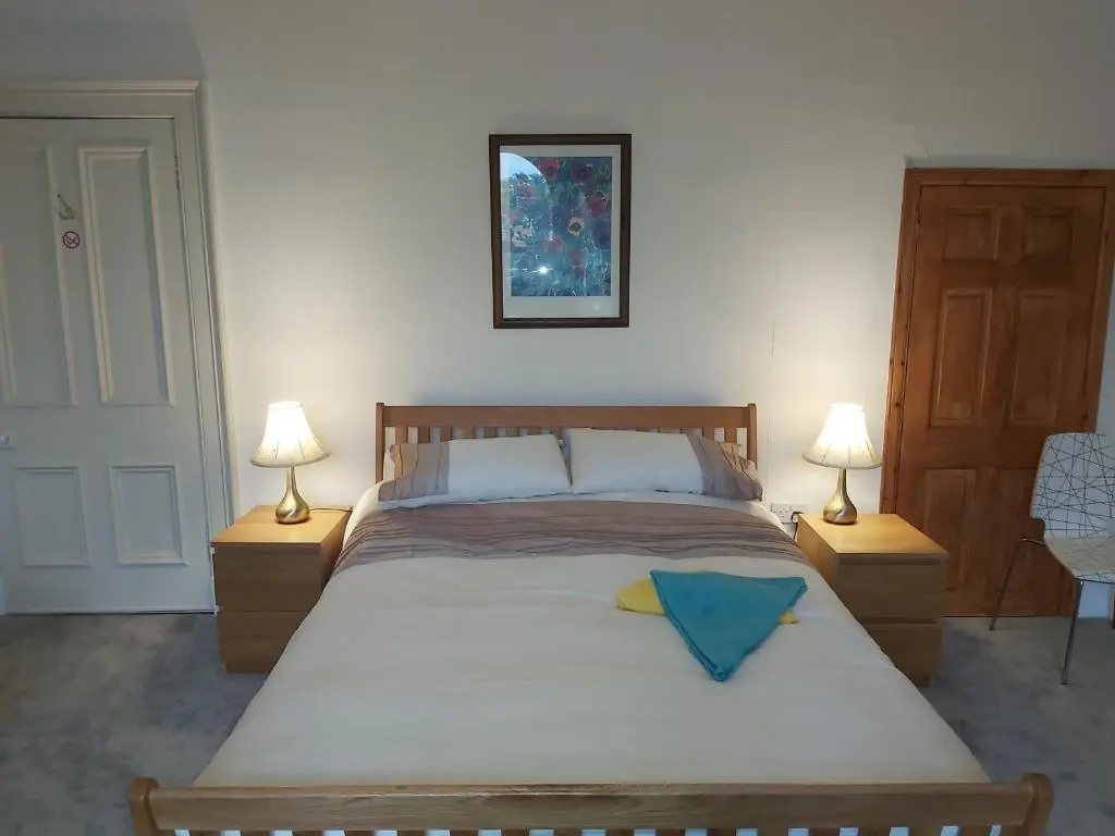 a bedroom with a large bed with two lamps at Kirkhouse in Wick