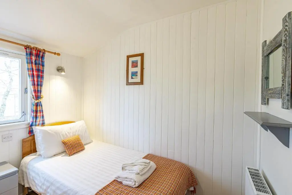 a small bedroom with a bed and a window at Heather Lodge 12 with Hot Tub in Belladrum