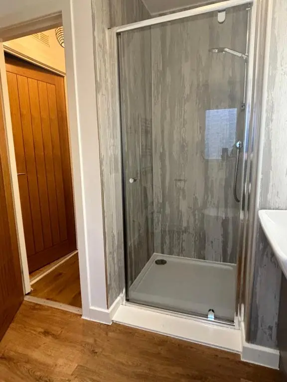 a shower with a glass door in a bathroom at Heather Lodge 12 with Hot Tub in Belladrum