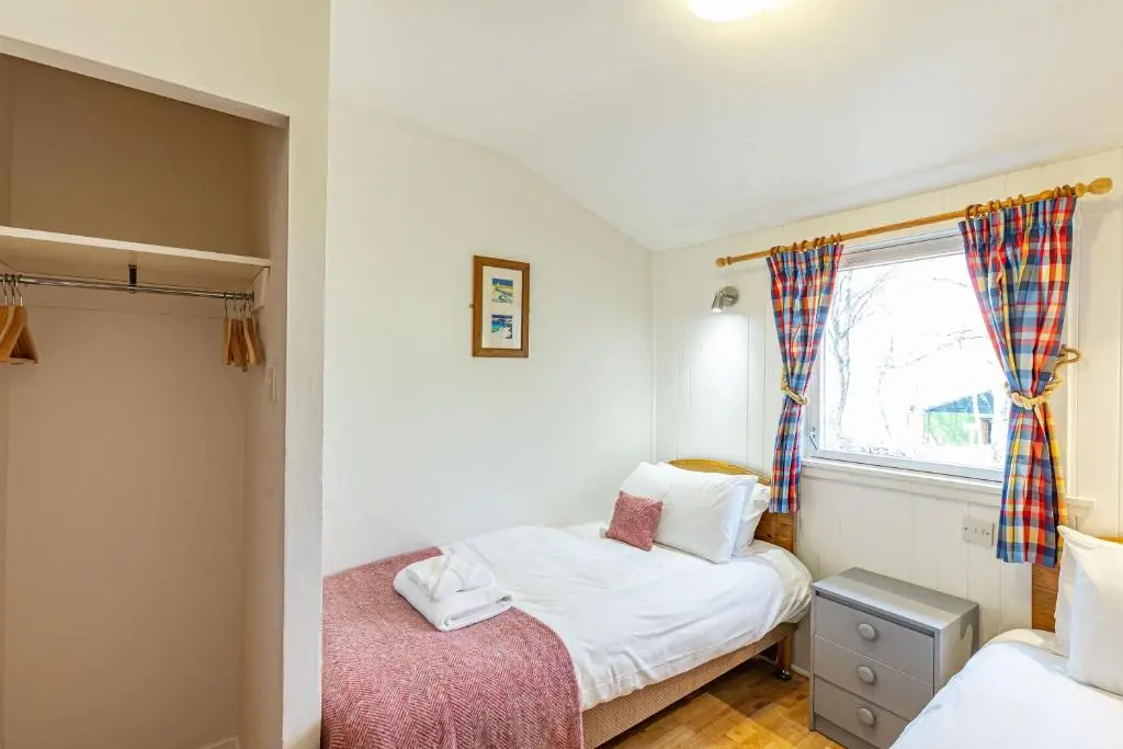 a small bedroom with two beds and a window at Heather Lodge 12 with Hot Tub in Belladrum