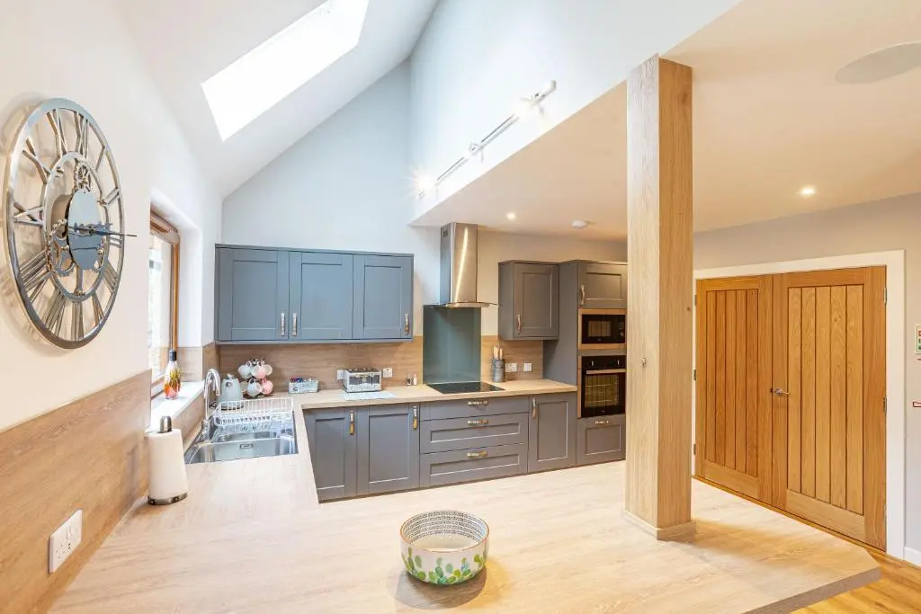 a kitchen with blue cabinets and a clock on the wall at Monarch Lodge 13 with Hot Tub in Belladrum