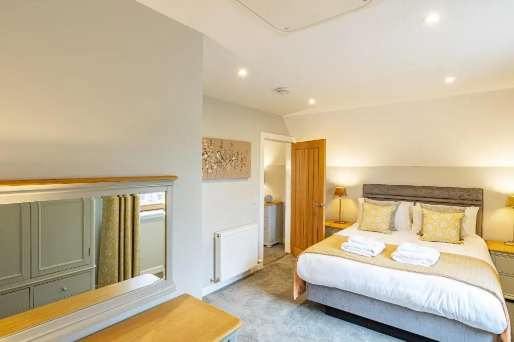 a bedroom with a large bed and a table at Monarch Lodge 13 with Hot Tub in Belladrum