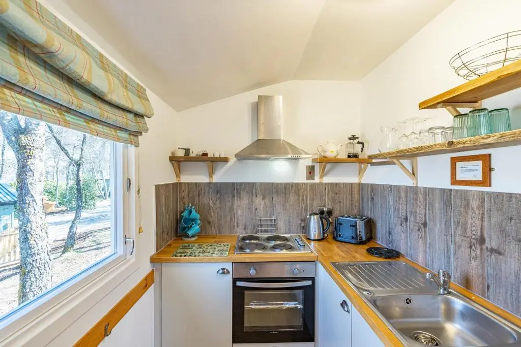 a kitchen with a sink and a stove and a window at Fern Lodge 11 with Hot Tub in Belladrum