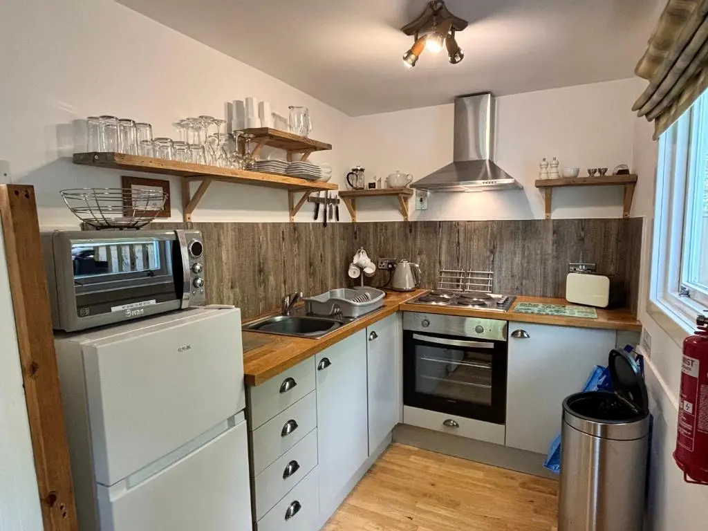 a kitchen with white cabinets and a microwave at Bracken Lodge 8 with Hot Tub in Belladrum