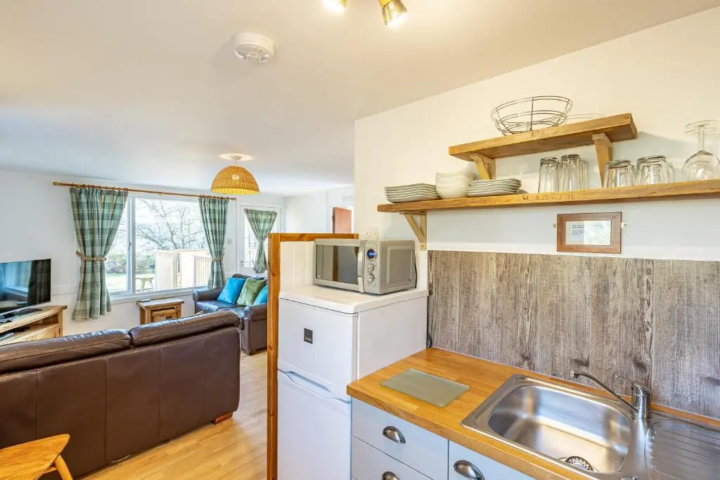 a kitchen with a sink and a living room at Bracken Lodge 16 with Hot Tub in Belladrum