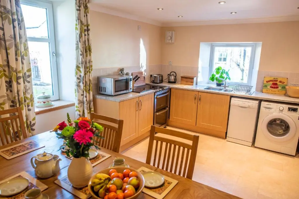 a kitchen with a table with a bowl of fruit on it at Hillside Cottage in Aberdeen