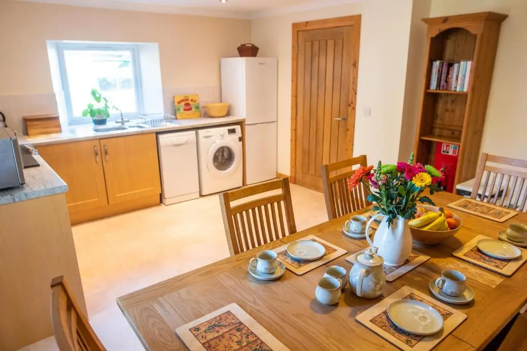 a kitchen and dining room with a wooden table at Hillside Cottage in Aberdeen