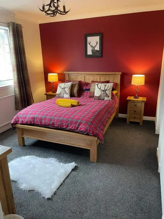 a bedroom with a bed with a red wall at Haste Ye Back in Inverness