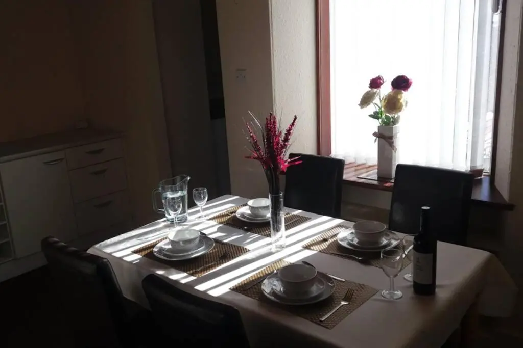 a dining room table with a white tablecloth and plates and glasses at Preston Villa, spacious ground floor apartment in Buckie