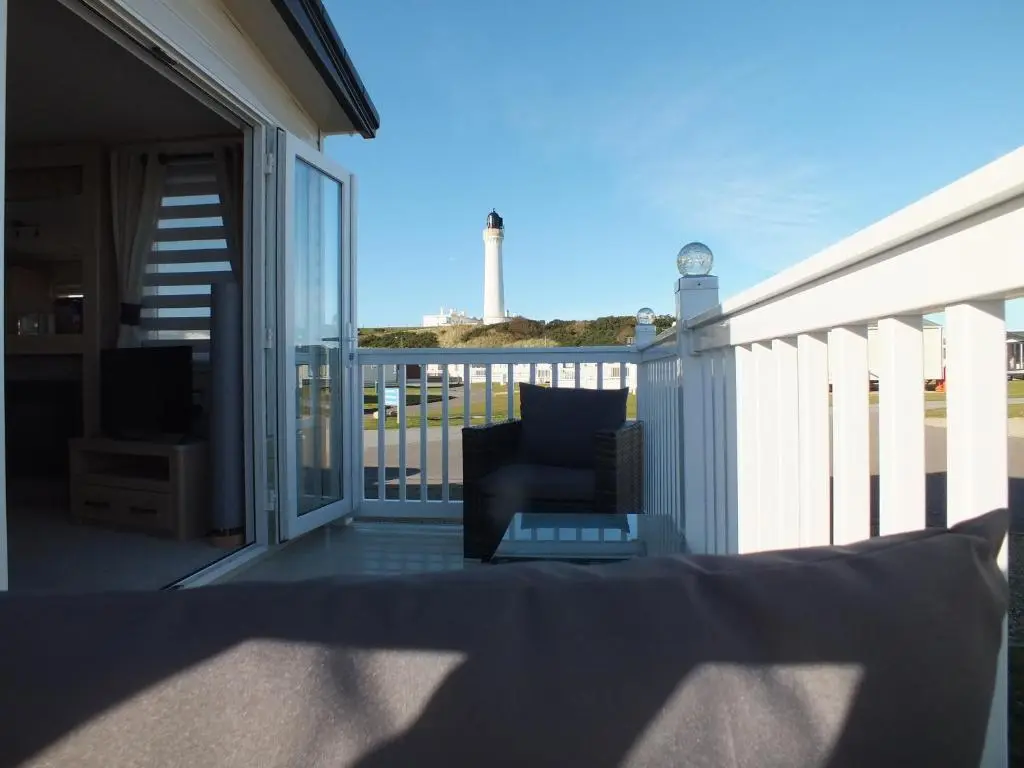 a balcony with a chair and a view of a lighthouse at Beachside Lighthouse 14 in Lossiemouth