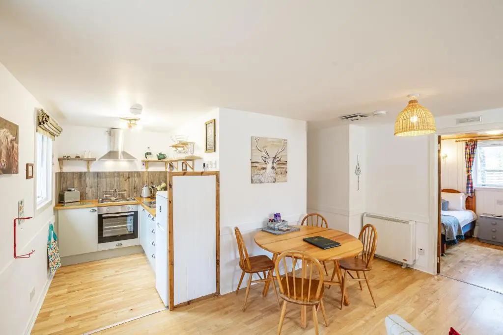 a kitchen and dining room with a table and chairs at Heather Lodge 4, sleeping 6 in Belladrum