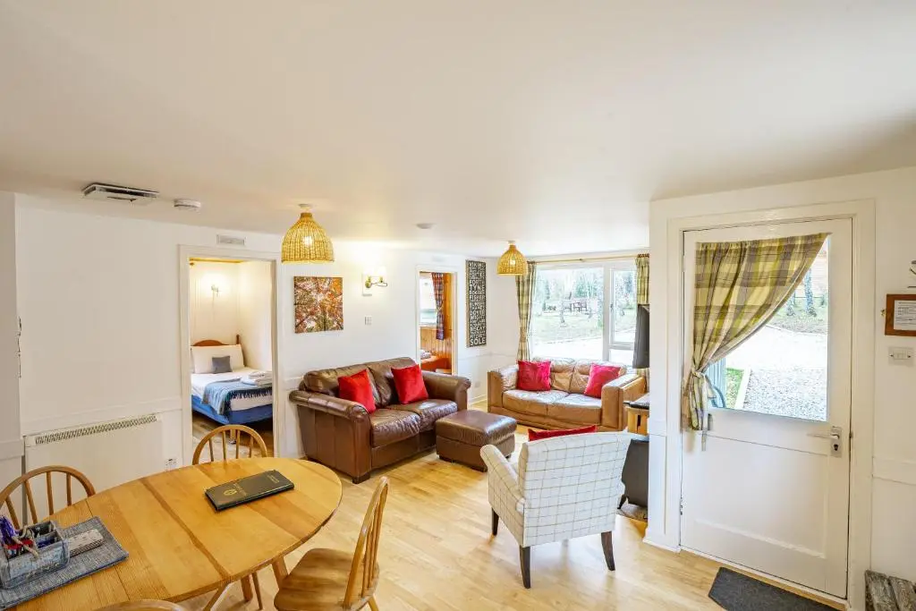 a living room with a table and a couch at Heather Lodge 4, sleeping 6 in Belladrum