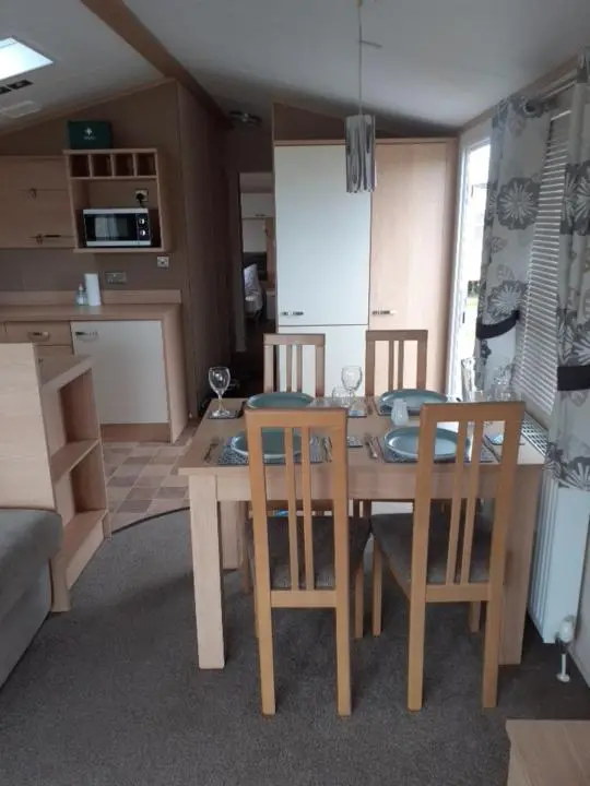 a kitchen with a dining room table and chairs at RICK'S RETREAT static caravan near the beach with free wifi in Lossiemouth
