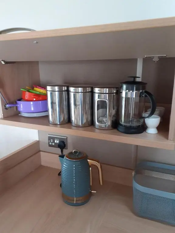 a row of pots and pans on a shelf at RICK'S RETREAT static caravan near the beach with free wifi in Lossiemouth