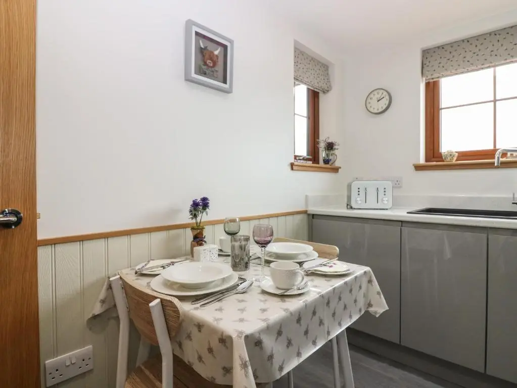 a kitchen with a table with plates and wine glasses at Garden Studio in Insch
