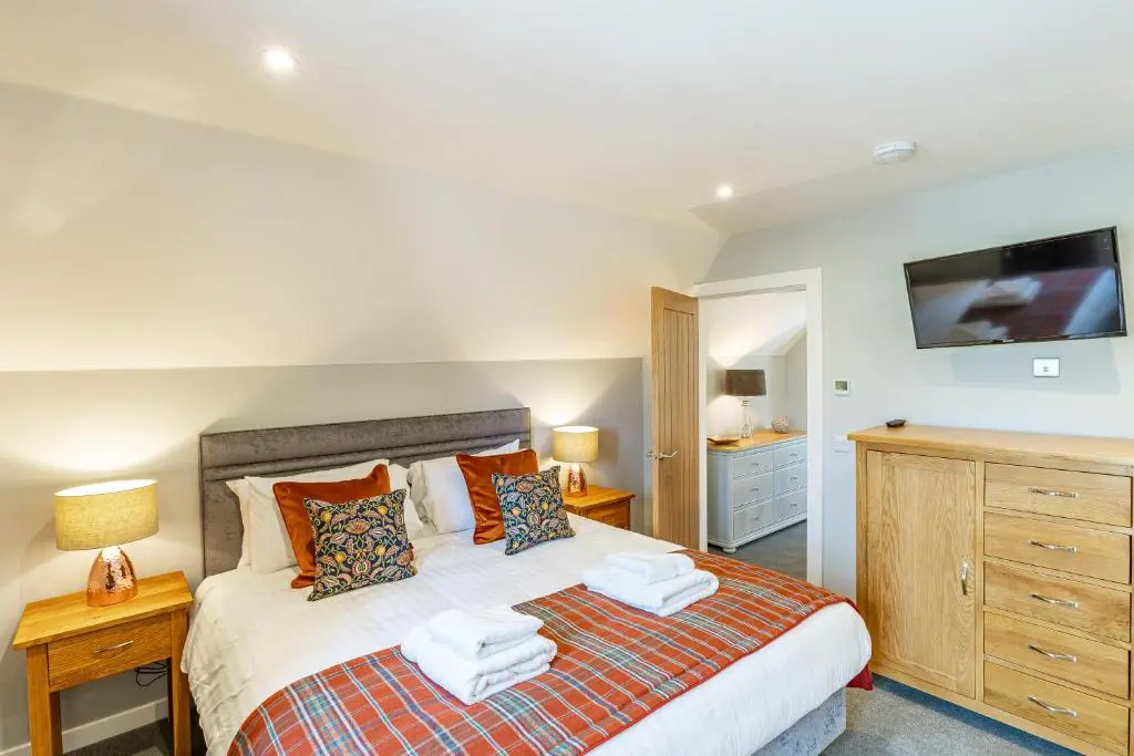 a bedroom with a bed and a tv on the wall at Monarch Lodge 14 with Hot Tub in Belladrum