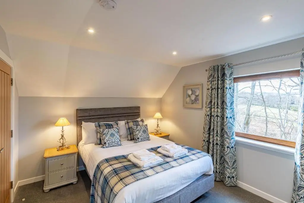 a bedroom with a bed and a window at Monarch Lodge 14 with Hot Tub in Belladrum