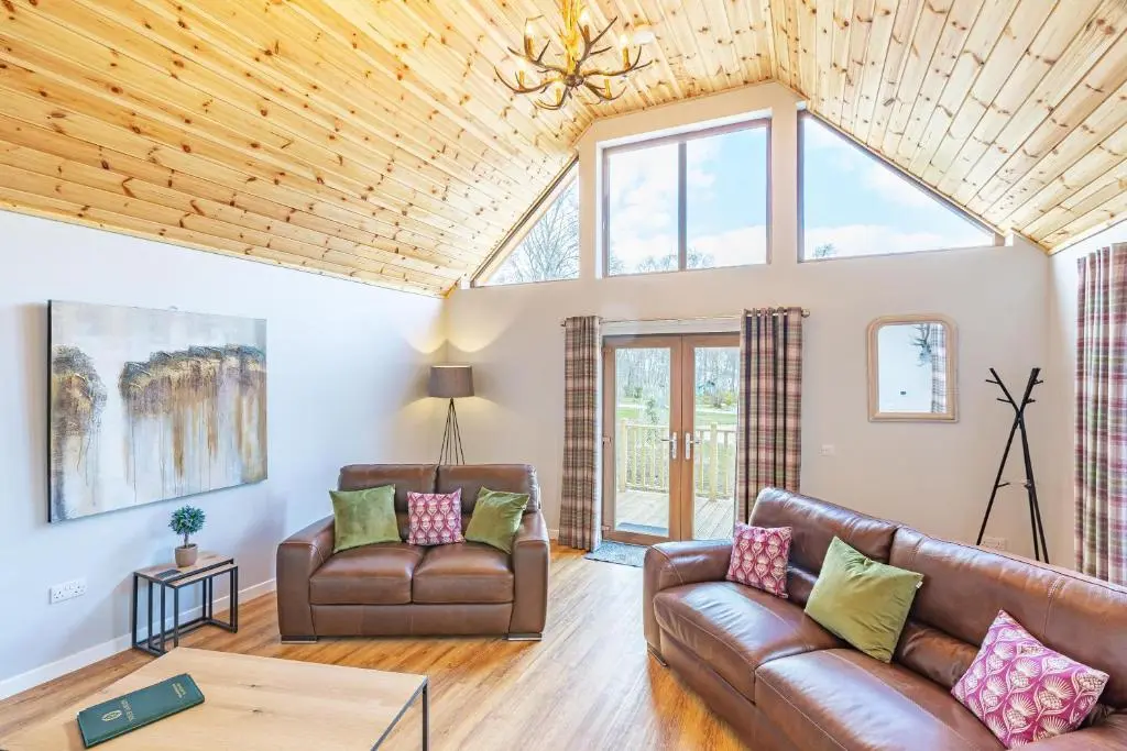 a living room with a couch and a table at Thistle Lodge 20 with Hot Tub in Belladrum
