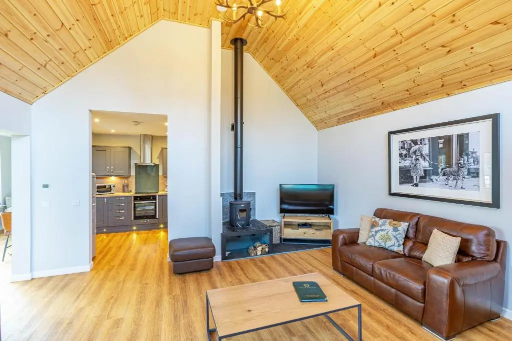 a living room with a couch and a table at Thistle Lodge 22 with Hot Tub in Belladrum