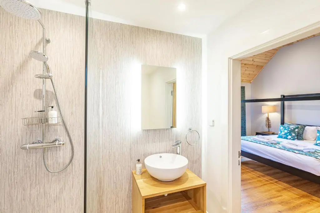 a bathroom with a sink and a shower and a bed at Thistle Lodge 22 with Hot Tub in Belladrum
