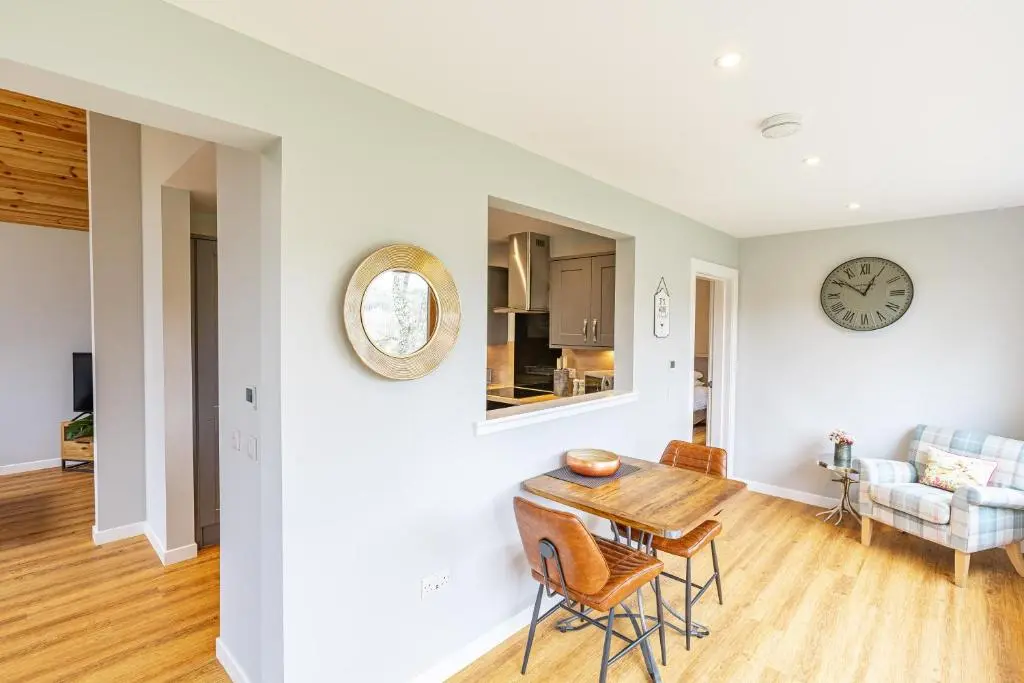 a dining room and living room with a table and chairs at Thistle Lodge 18 with Hot Tub in Belladrum
