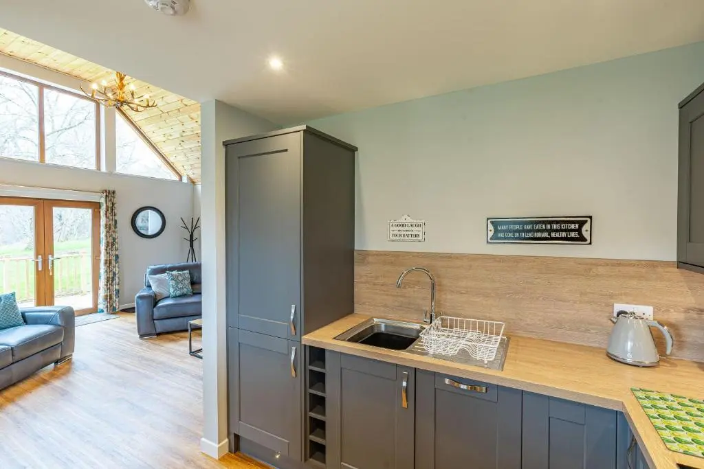a kitchen with a sink and a living room at Thistle Lodge 18 with Hot Tub in Belladrum