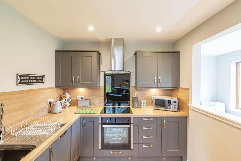 a kitchen with gray cabinets and a sink at Thistle Lodge 18 with Hot Tub in Belladrum
