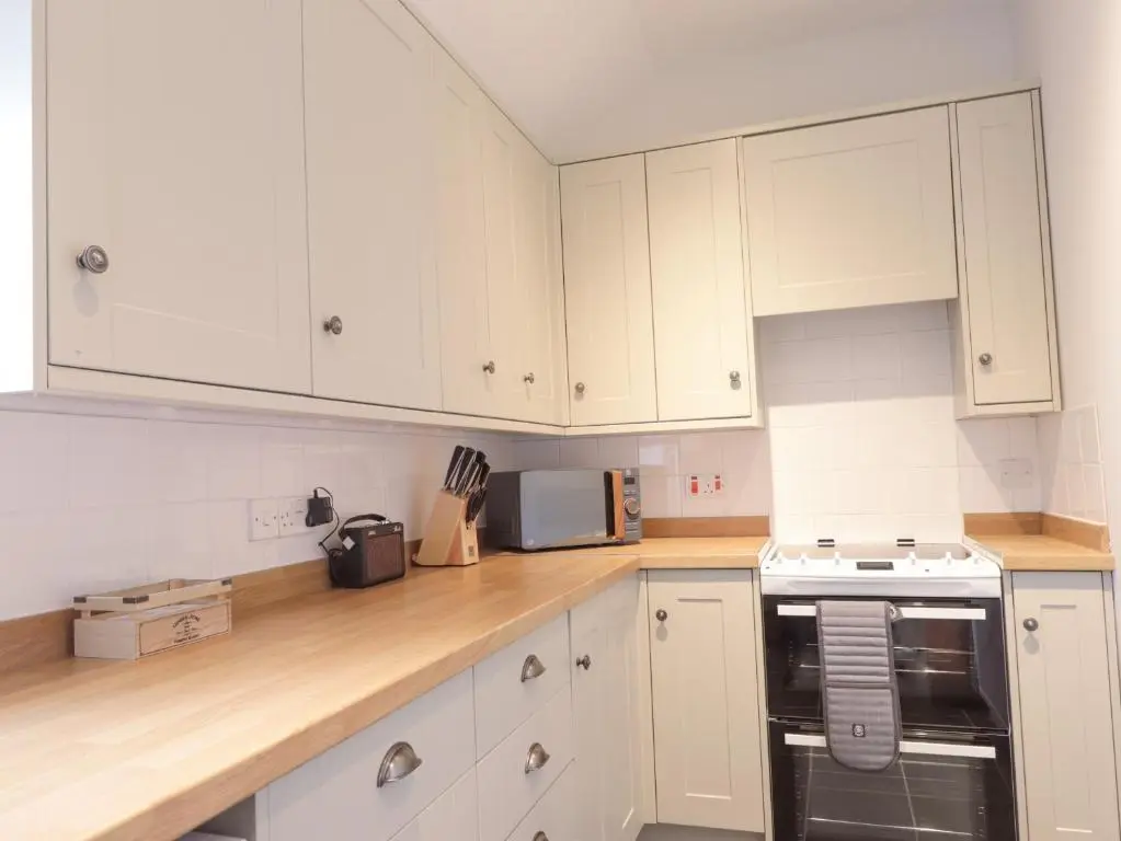 a kitchen with white cabinets and a stove top oven at Garden House - Brodie Castle in Forres