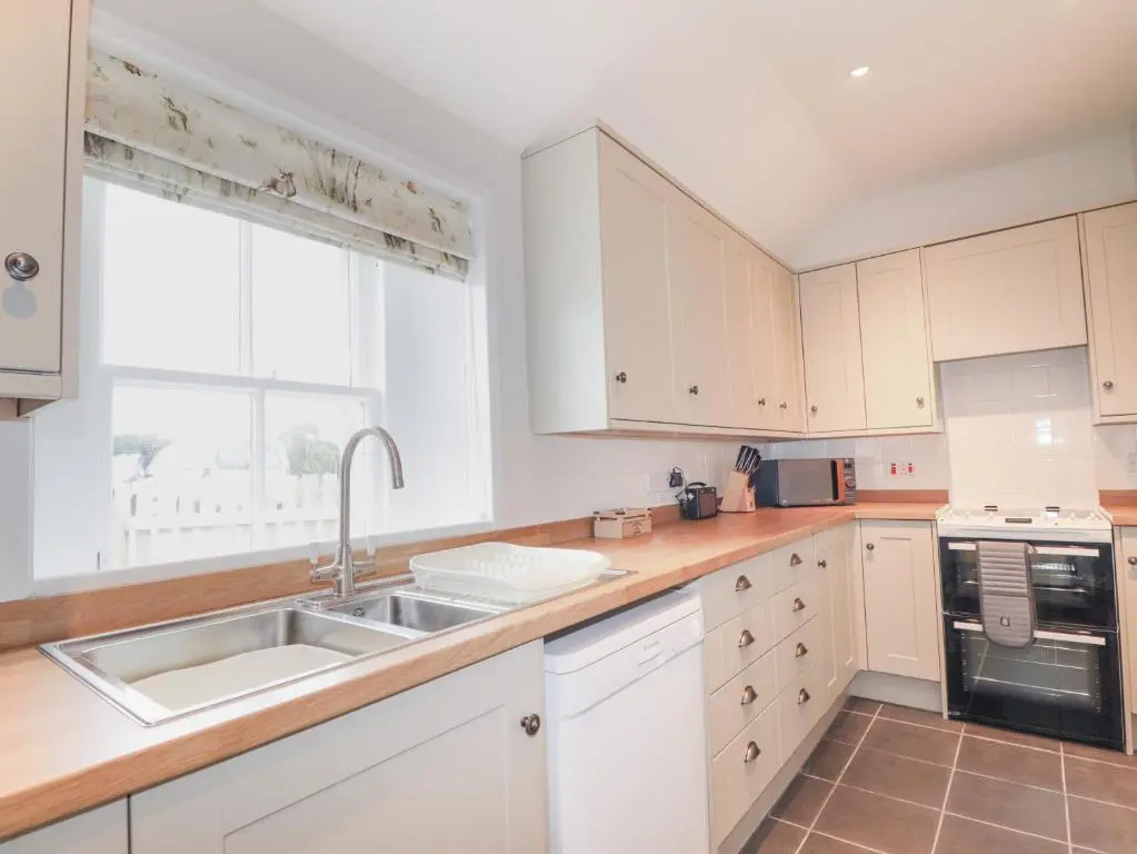 a kitchen with white cabinets and a sink and a window at Garden House - Brodie Castle in Forres