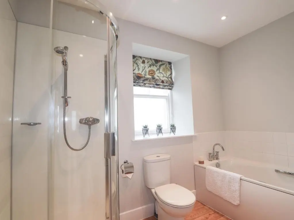 a bathroom with a toilet and a shower and a window at Garden House - Brodie Castle in Forres