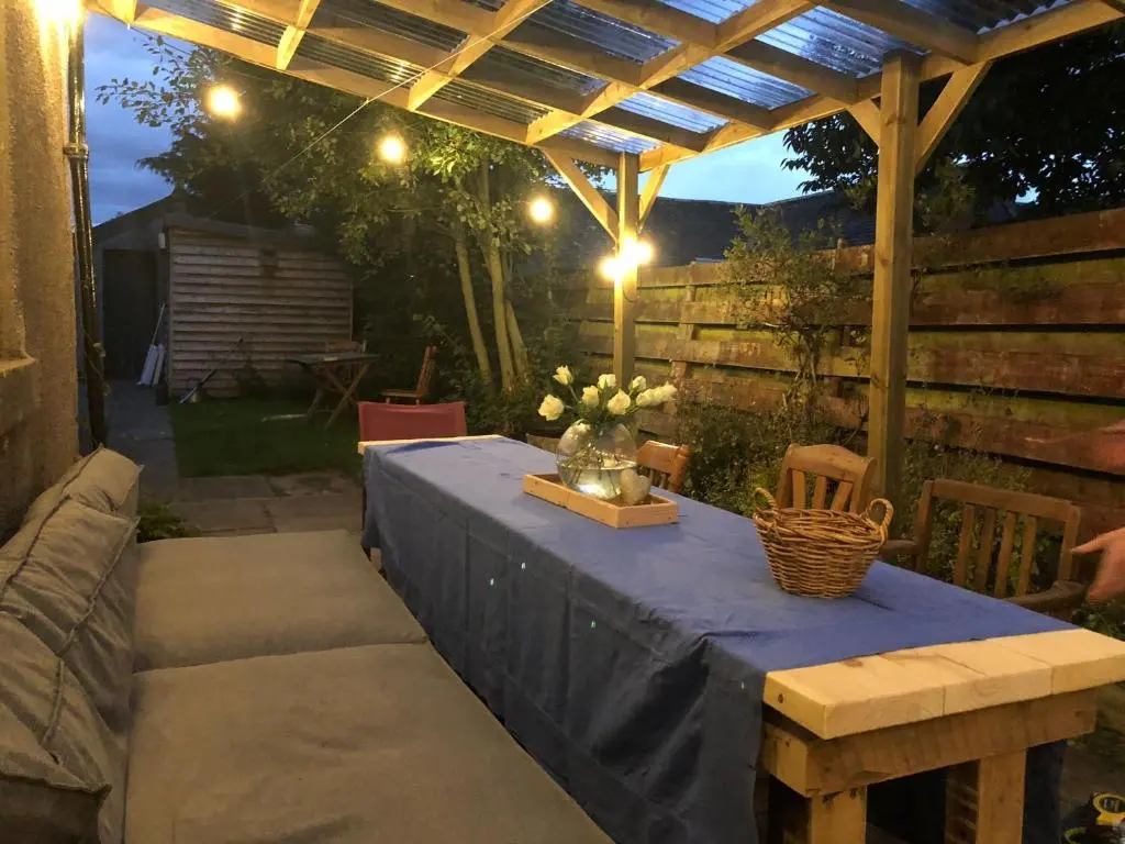 a table under a pergola with flowers on it at Nurse's Cottage in Tomintoul