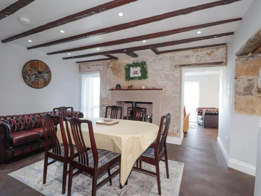 a dining room with a table and chairs and a fireplace at Seaview at The Doocot in Elgin