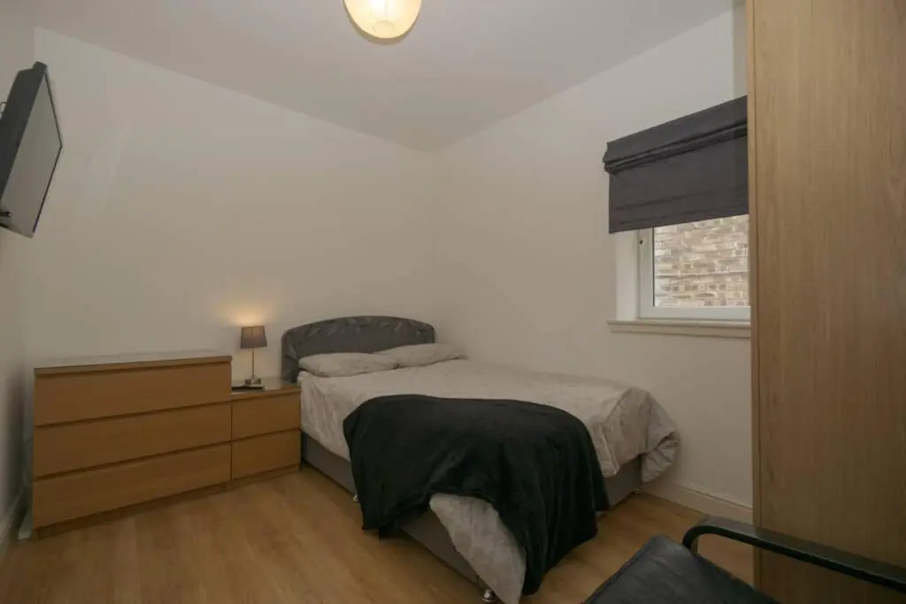 a bedroom with a bed and a dresser and a window at Town centre 4xbed 4xbath apartment in Elgin