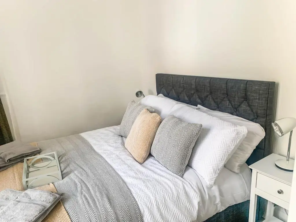 a bedroom with a bed with white sheets and pillows at The Rosebery Retreat By The Castle 1-Bed Apartment in Inverness
