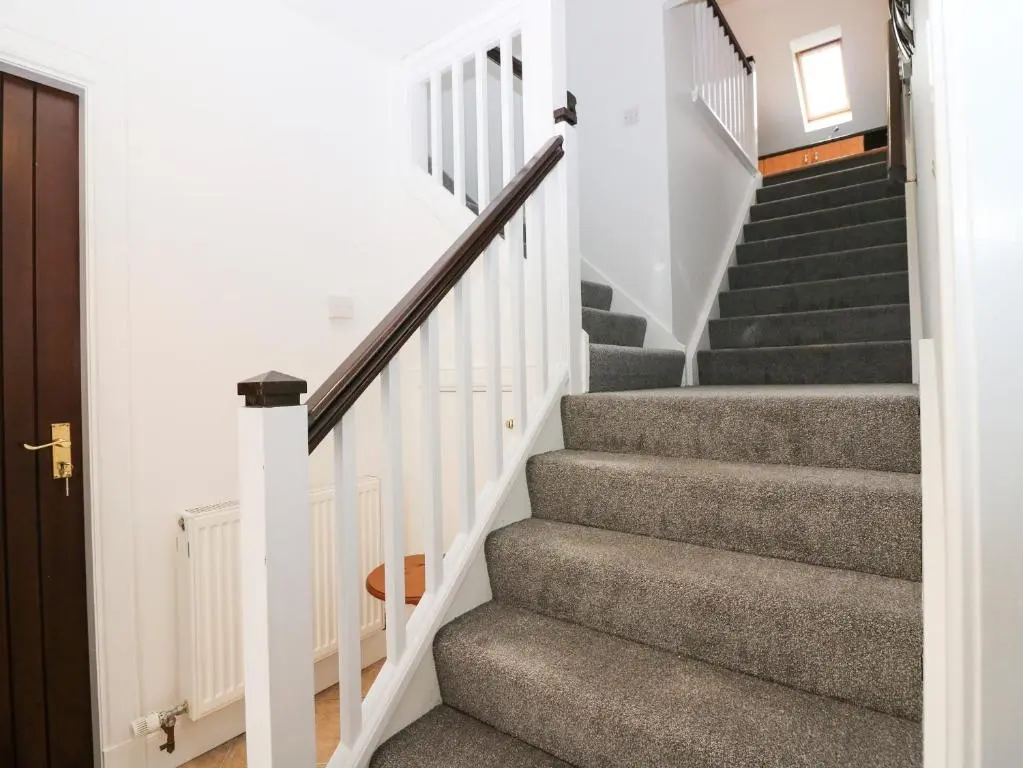 a staircase with white railings and gray carpet at Hayloft in Peterhead