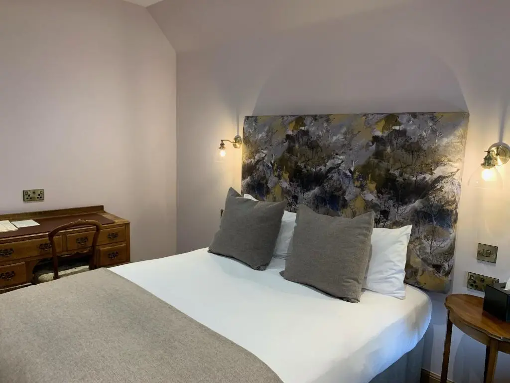 a bedroom with a white bed with a painting on the wall at Saplinbrae Hotel and Lodges in Mintlaw