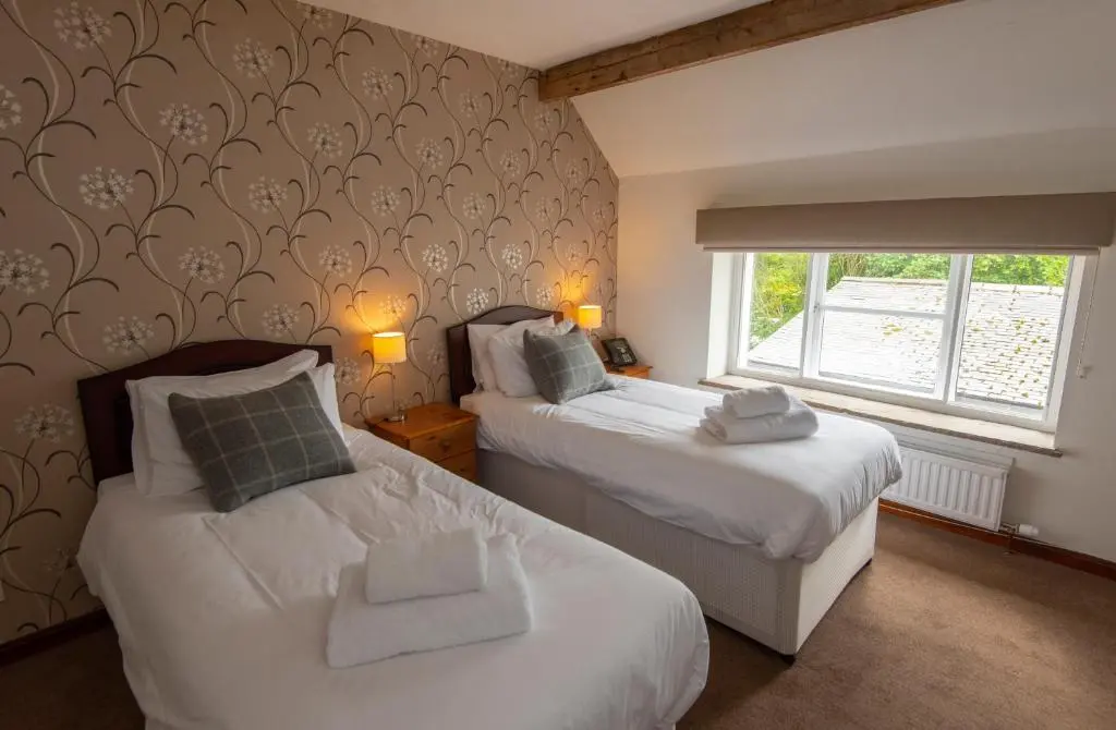 a bedroom with two beds and a window at Saplinbrae Hotel and Lodges in Mintlaw